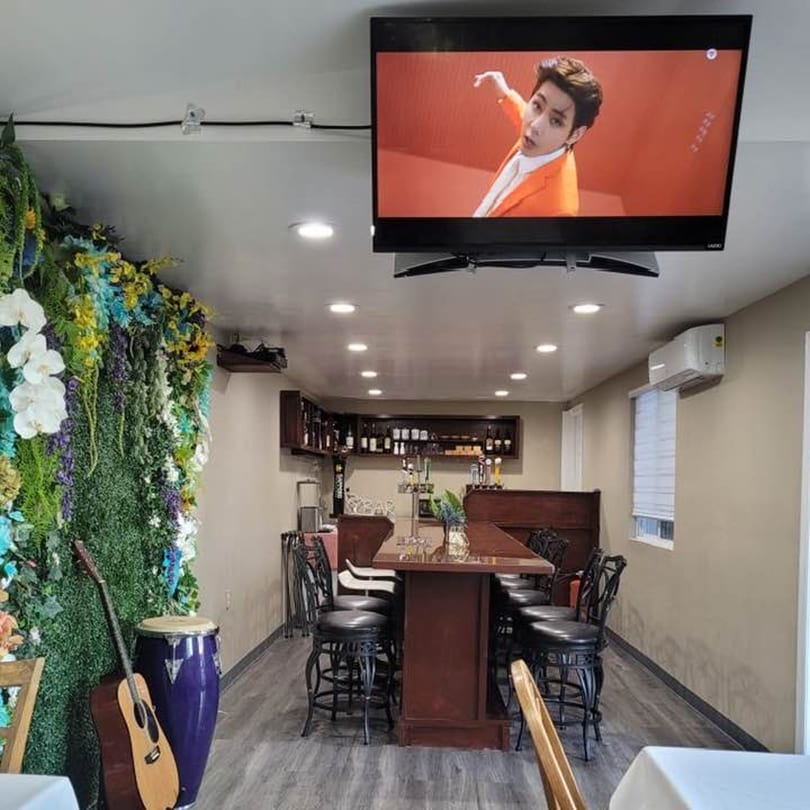 Interior of Tokyo Sushi Korean BBQ with a bar, high-top tables, and a TV playing K-pop.